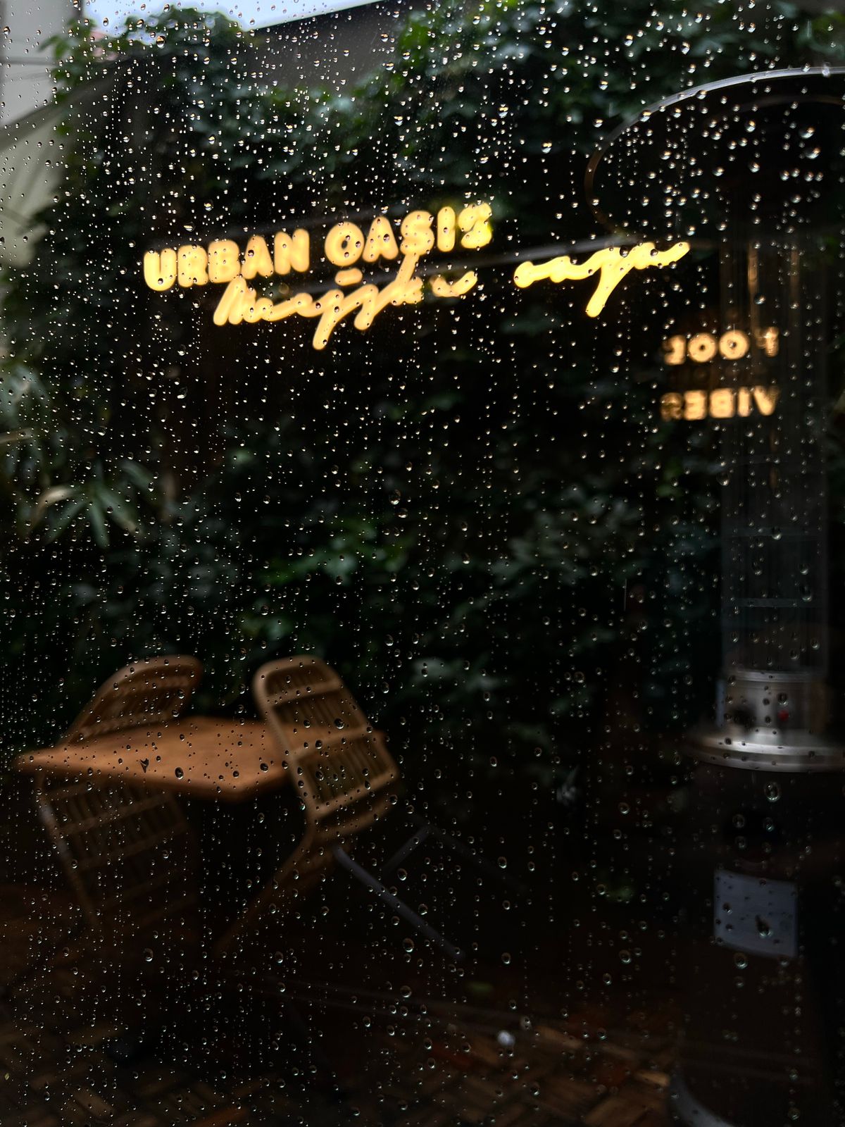 Rain-covered cafe window with a glowing neon sign